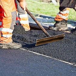 People in orange work gear paving a road